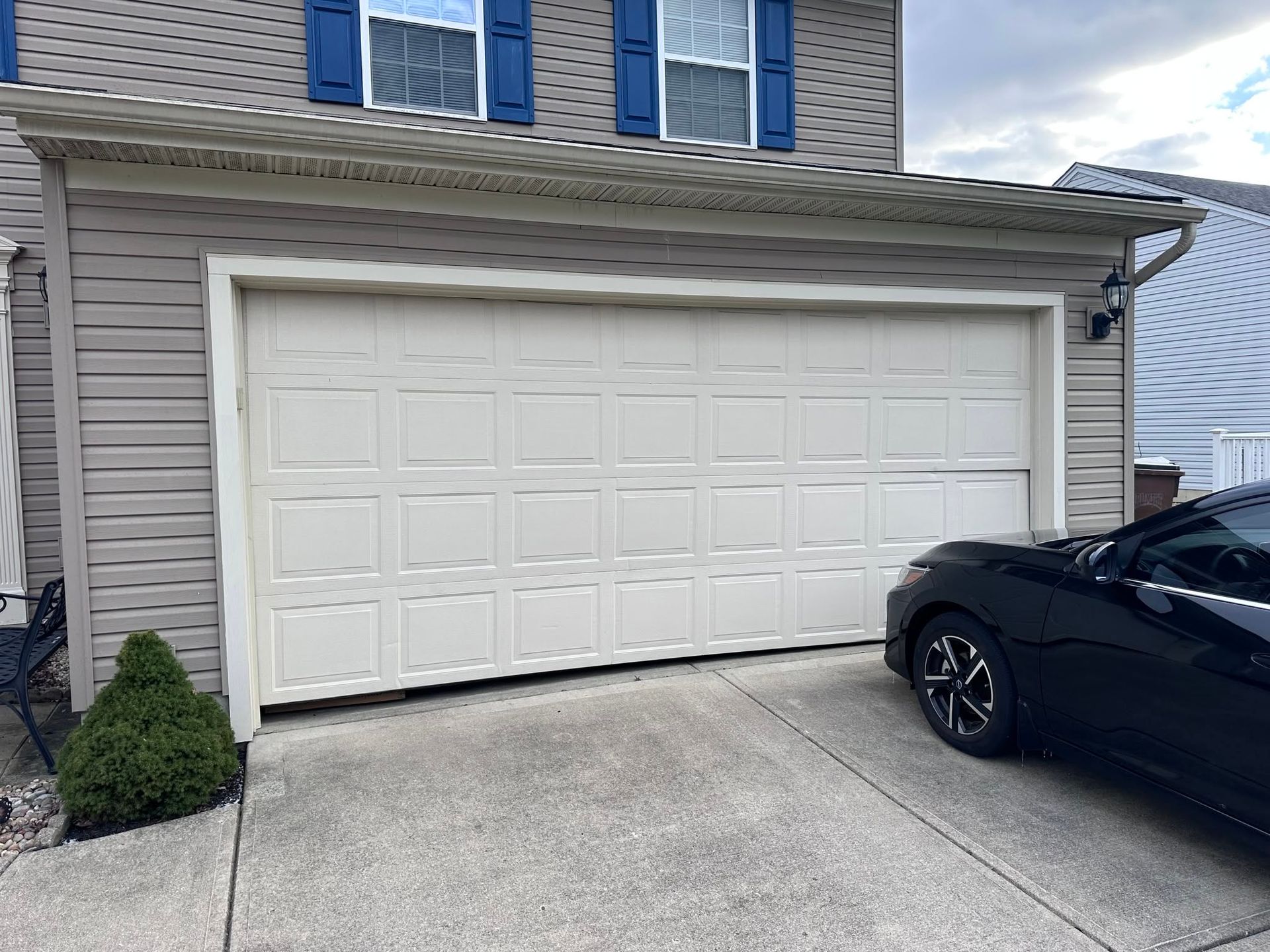 White two-car garage with a black car parked at the driveway edge