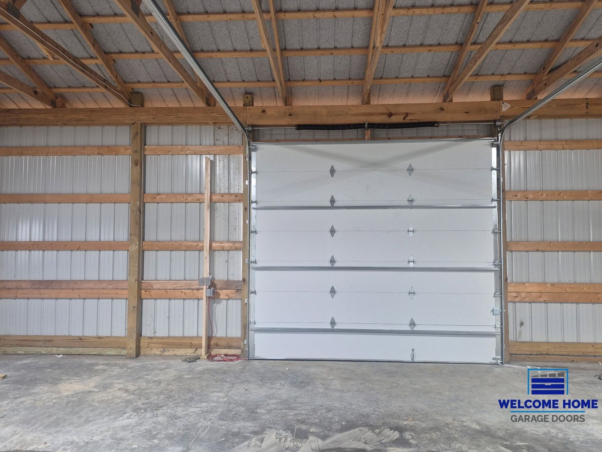 Interior of a wooden garage with a closed white overhead door and concrete floor