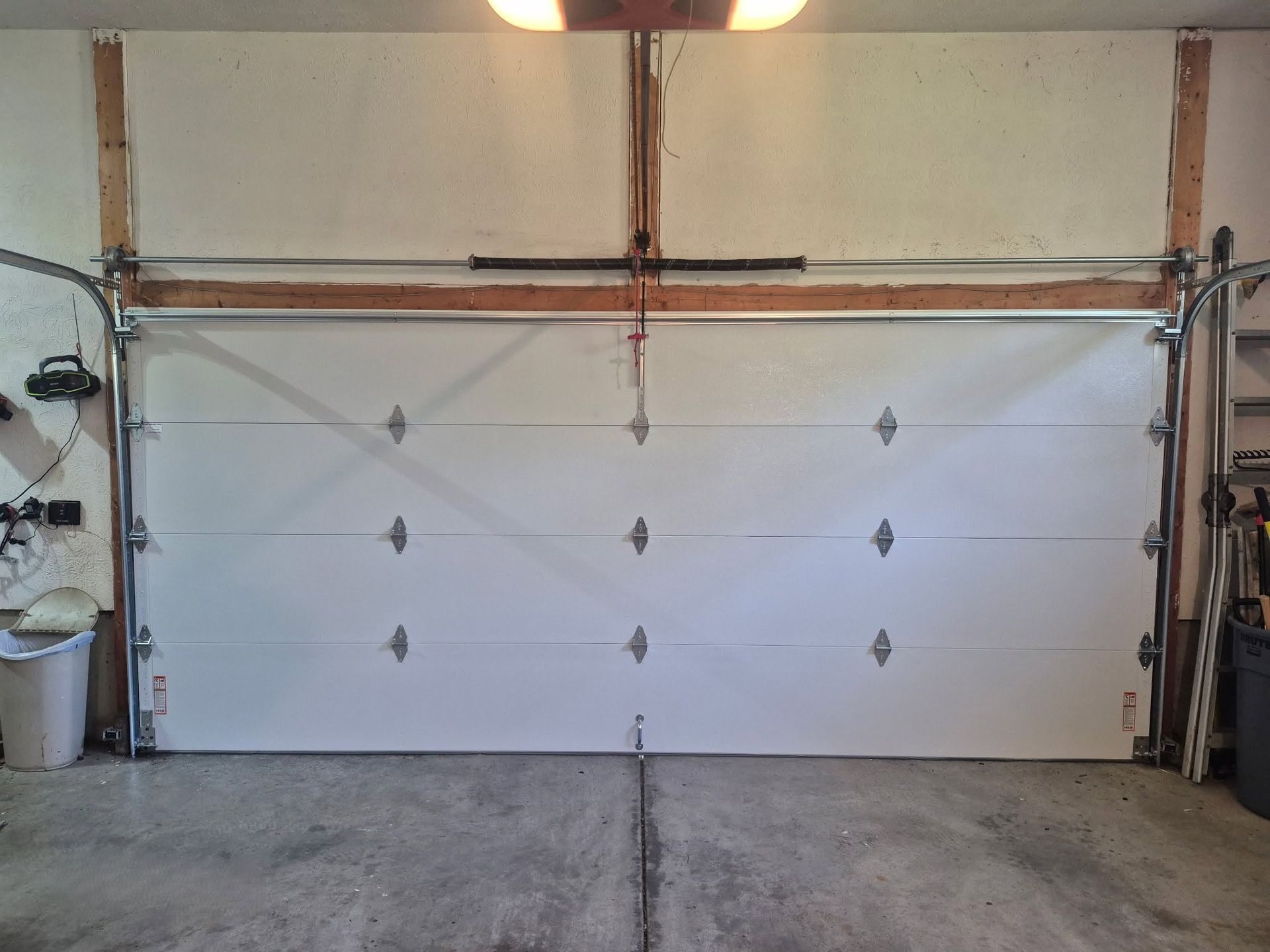 Closed white garage door with metal hardware in a concrete garage interior