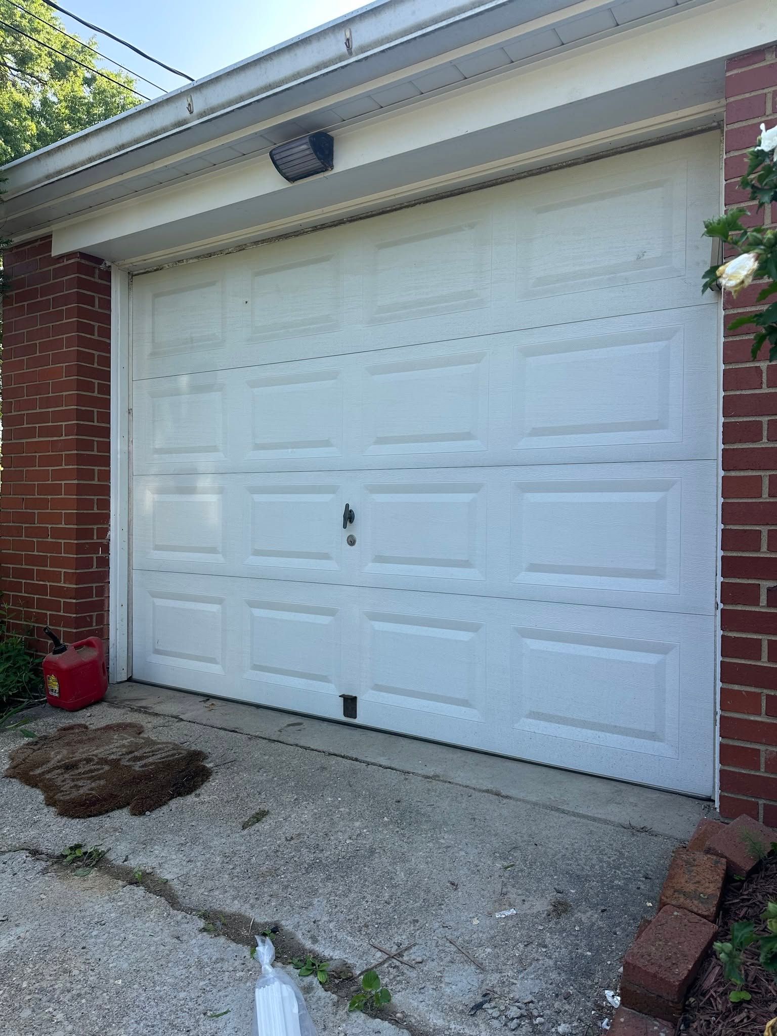White double garage door on a brick house with a concrete driveway and small front planting area