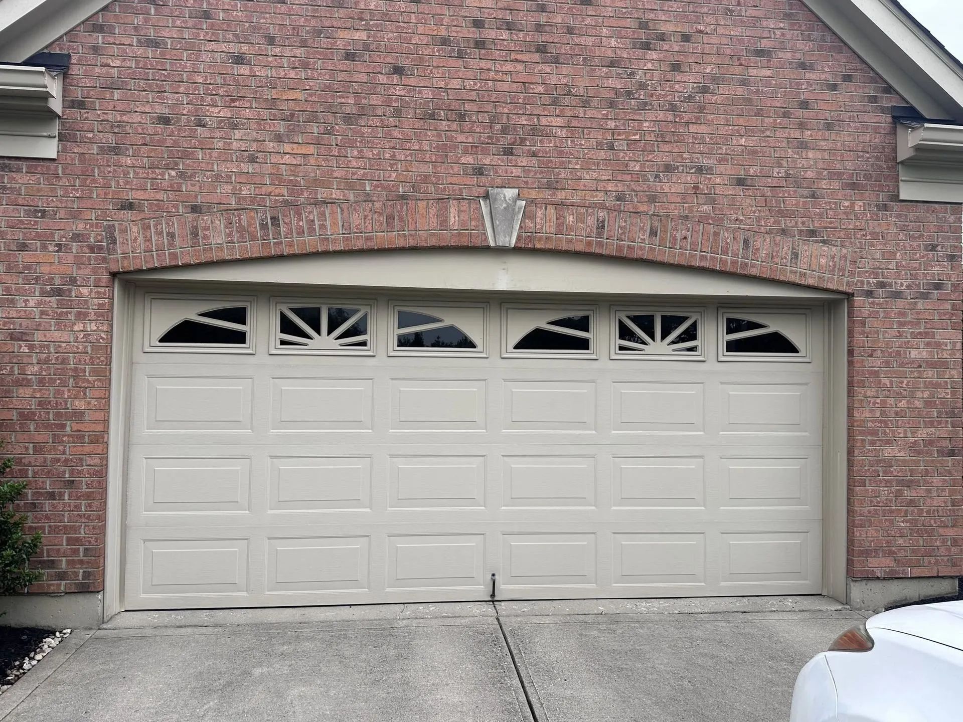 Beige four-car garage door on a brick house exterior