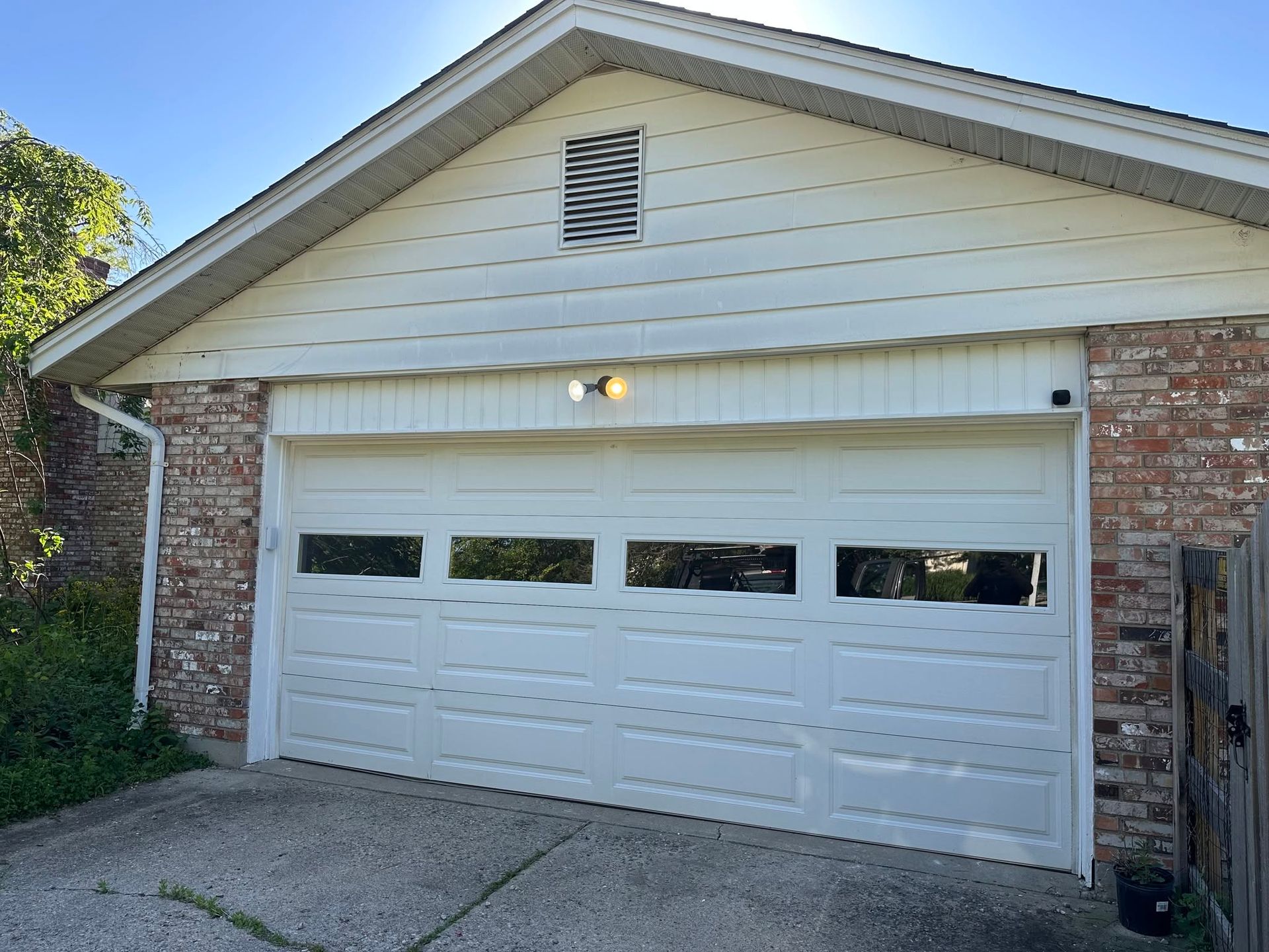 White garage door on a brick-and-siding house exterior under a peaked roof.