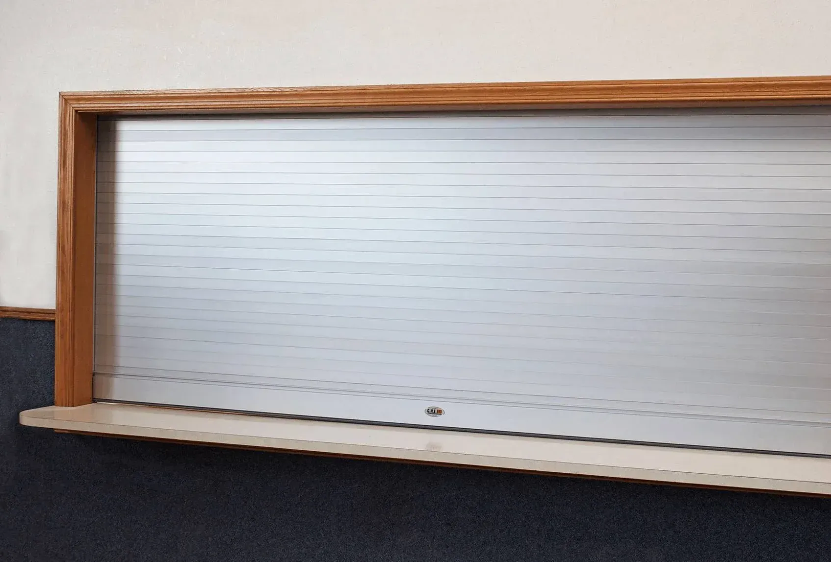Wooden-framed white slatted roll-up window or cabinet door with a narrow shelf below
