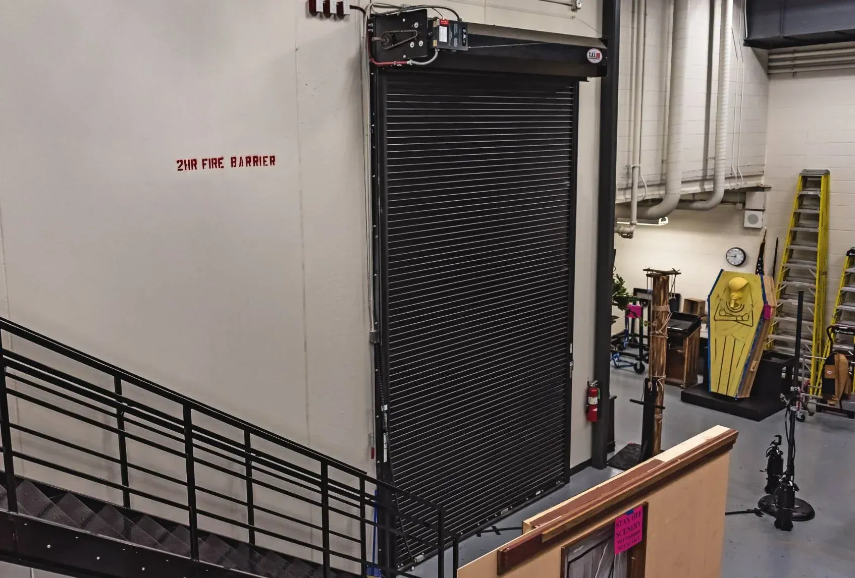 Industrial room with a large black HVAC unit, pipes, and a ladder along the wall.