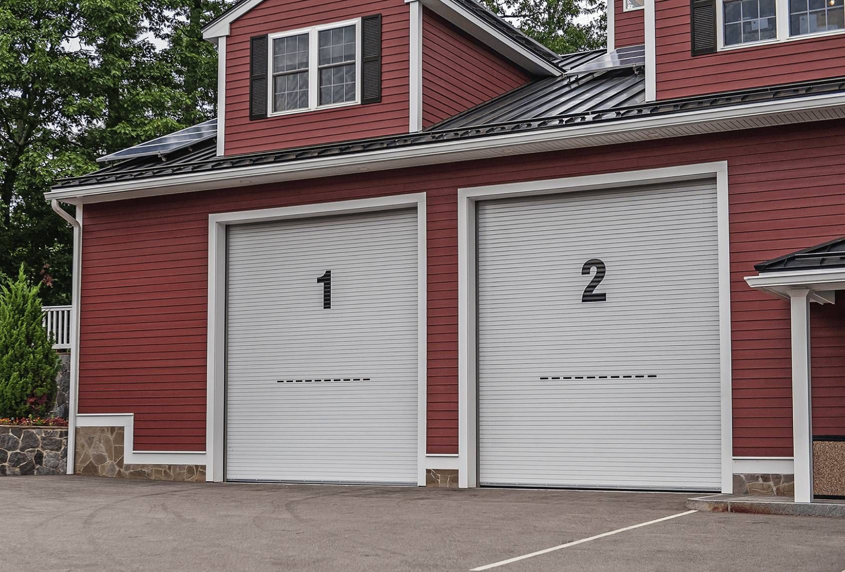 Two white garage doors numbered 1 and 2 on a red building