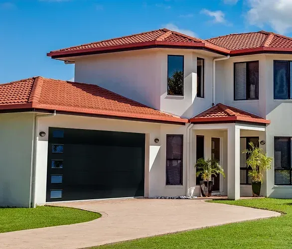 Modern two-story house with red tile roof, white exterior, and attached garage