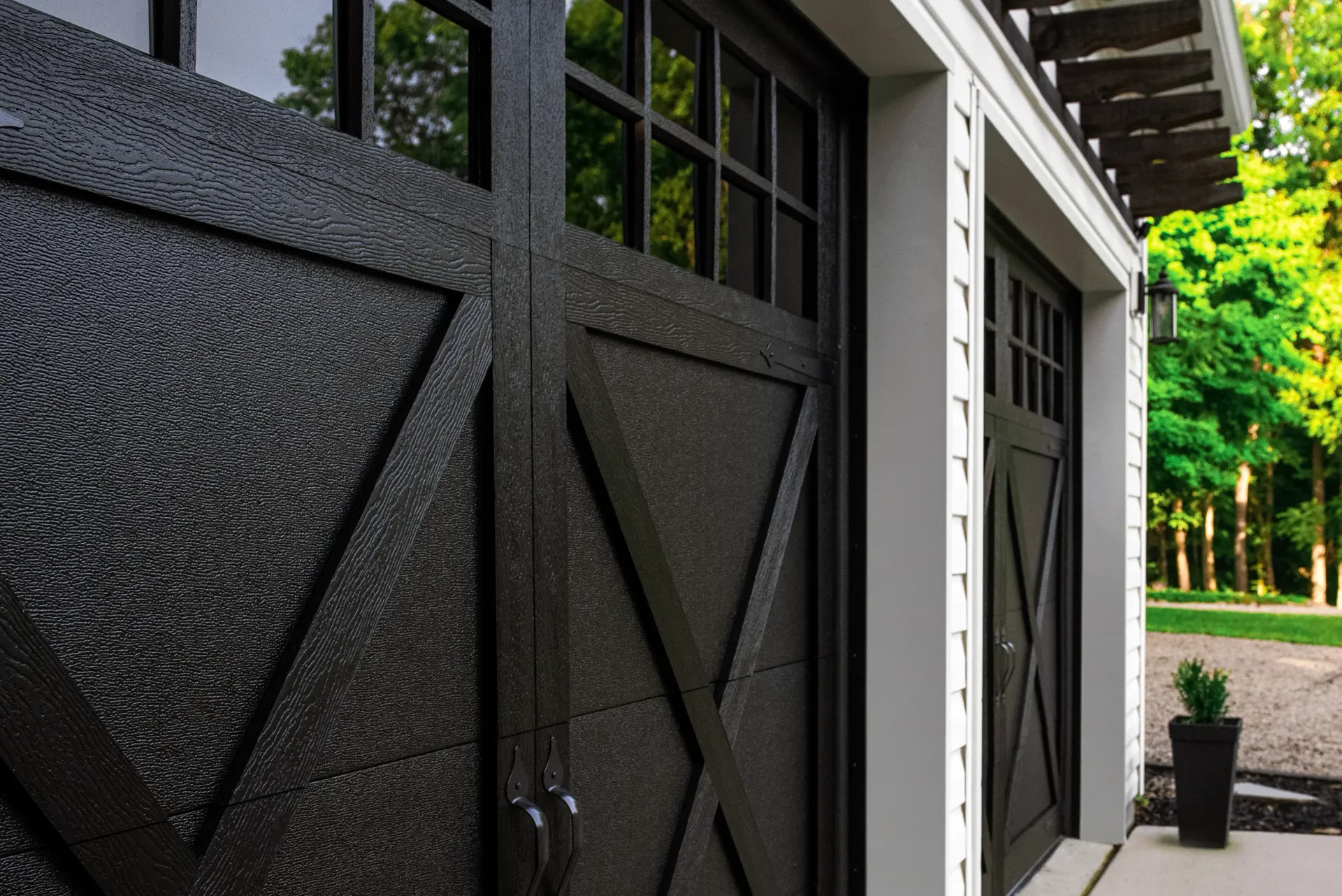 Black wooden building exterior with paneled doors and a tree-lined walkway nearby