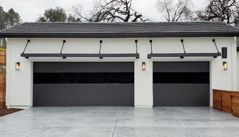 Modern white two-car garage with dark doors and concrete driveway