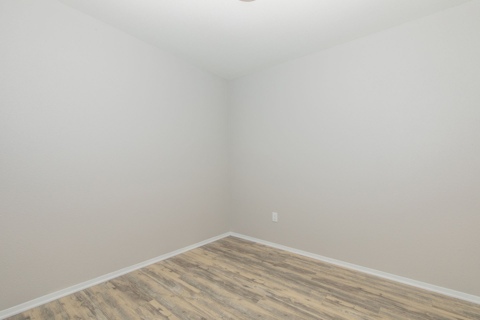 An empty room with a wooden floor and white walls.
