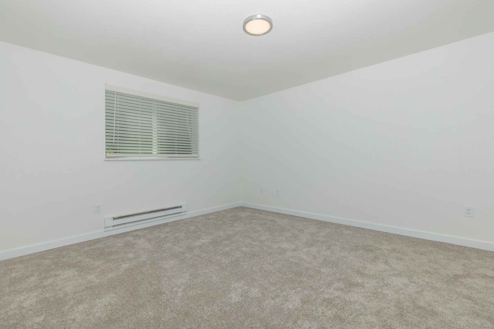 An empty bedroom with a window and a light on the ceiling.