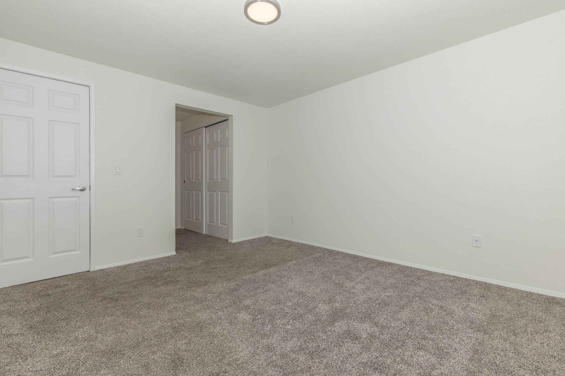 An empty bedroom with a carpeted floor and white walls.