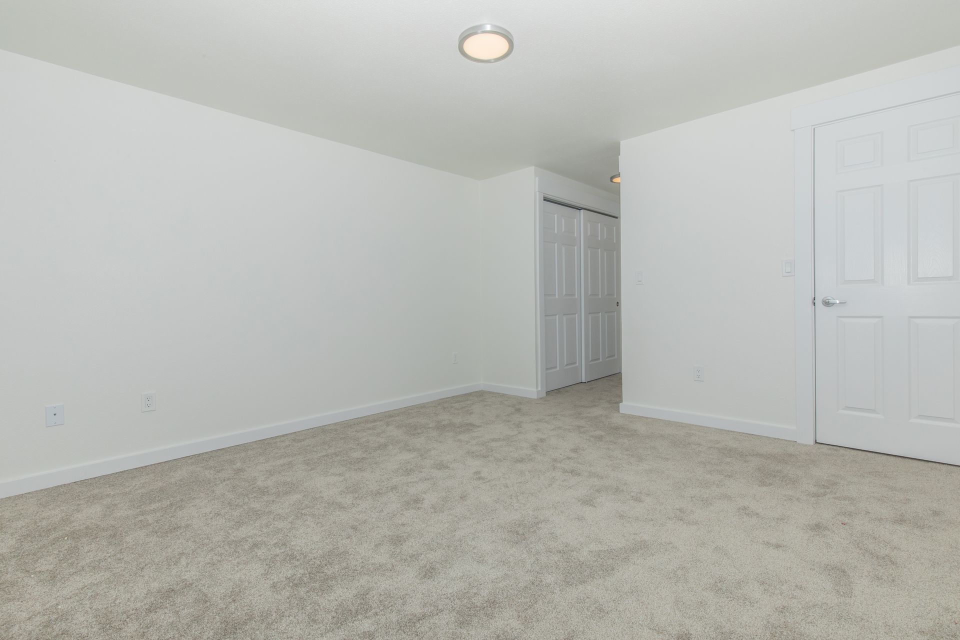 An empty bedroom with a carpeted floor and white walls.