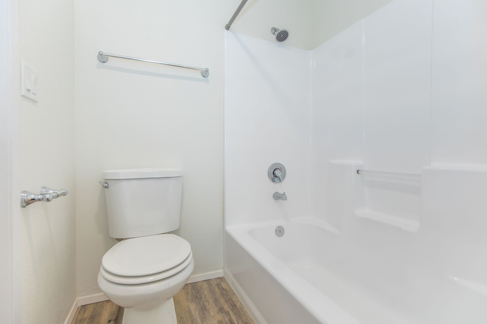 A bathroom with a toilet , bathtub and shower.