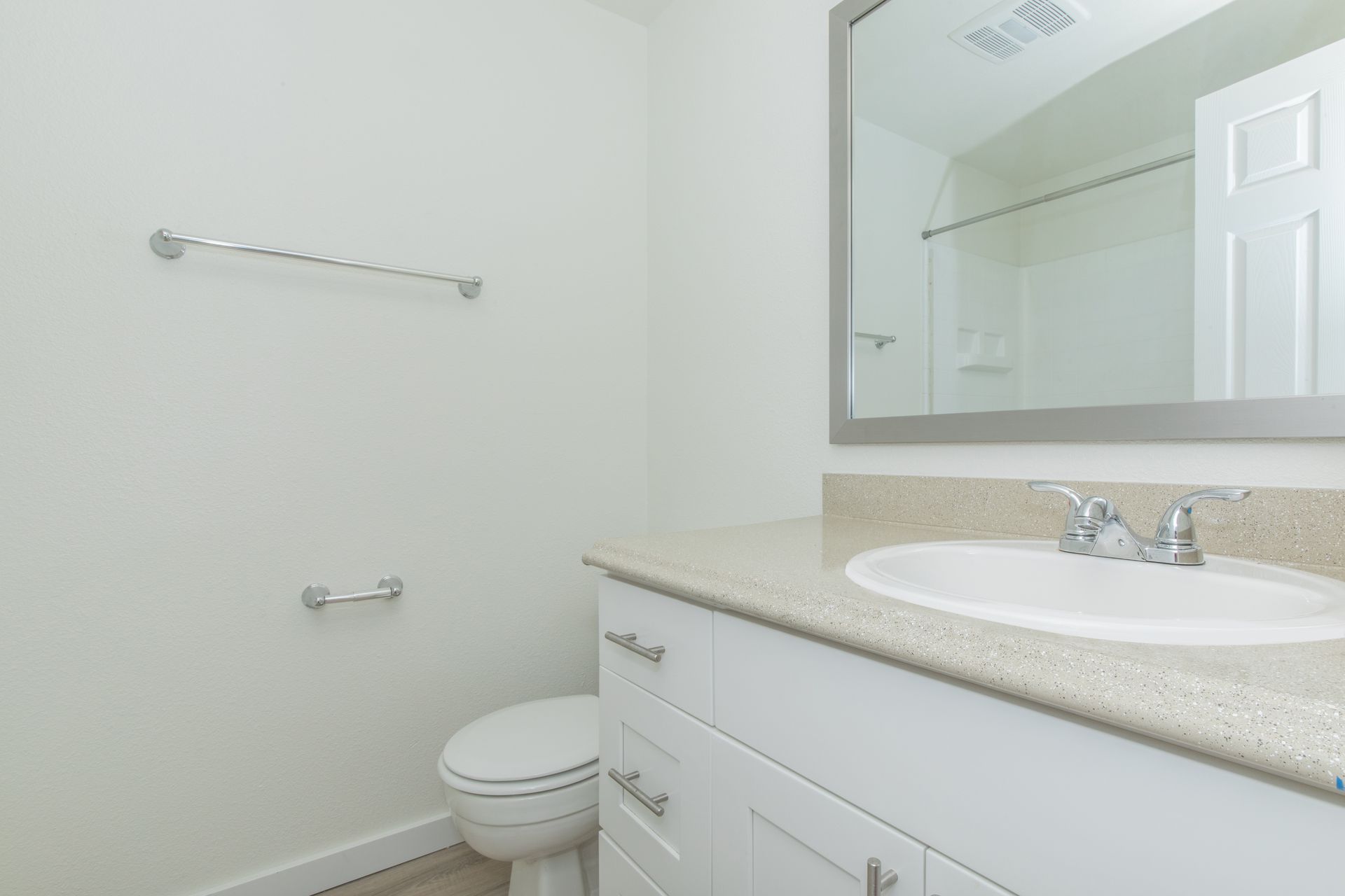 A bathroom with a toilet , sink and mirror.