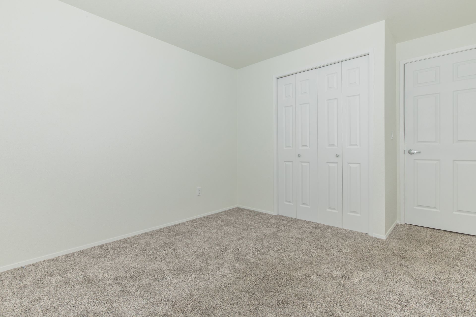An empty bedroom with a carpeted floor and white walls.