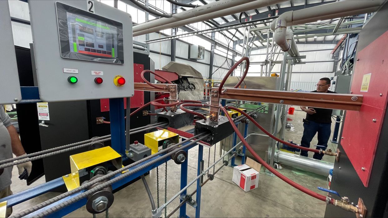 Factory machine automation machine and conveyor belts moving red tubing through induction machinery