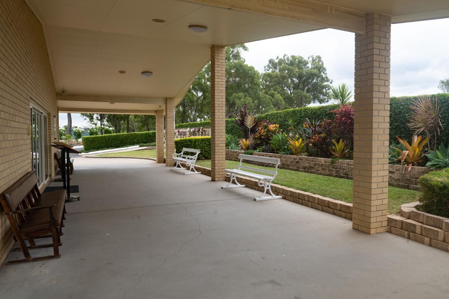 A Covered Patio Area with Benches, Overlooking a Well-Manicured Garden — Rockhampton Crematorium in Norman Gardens, QLD