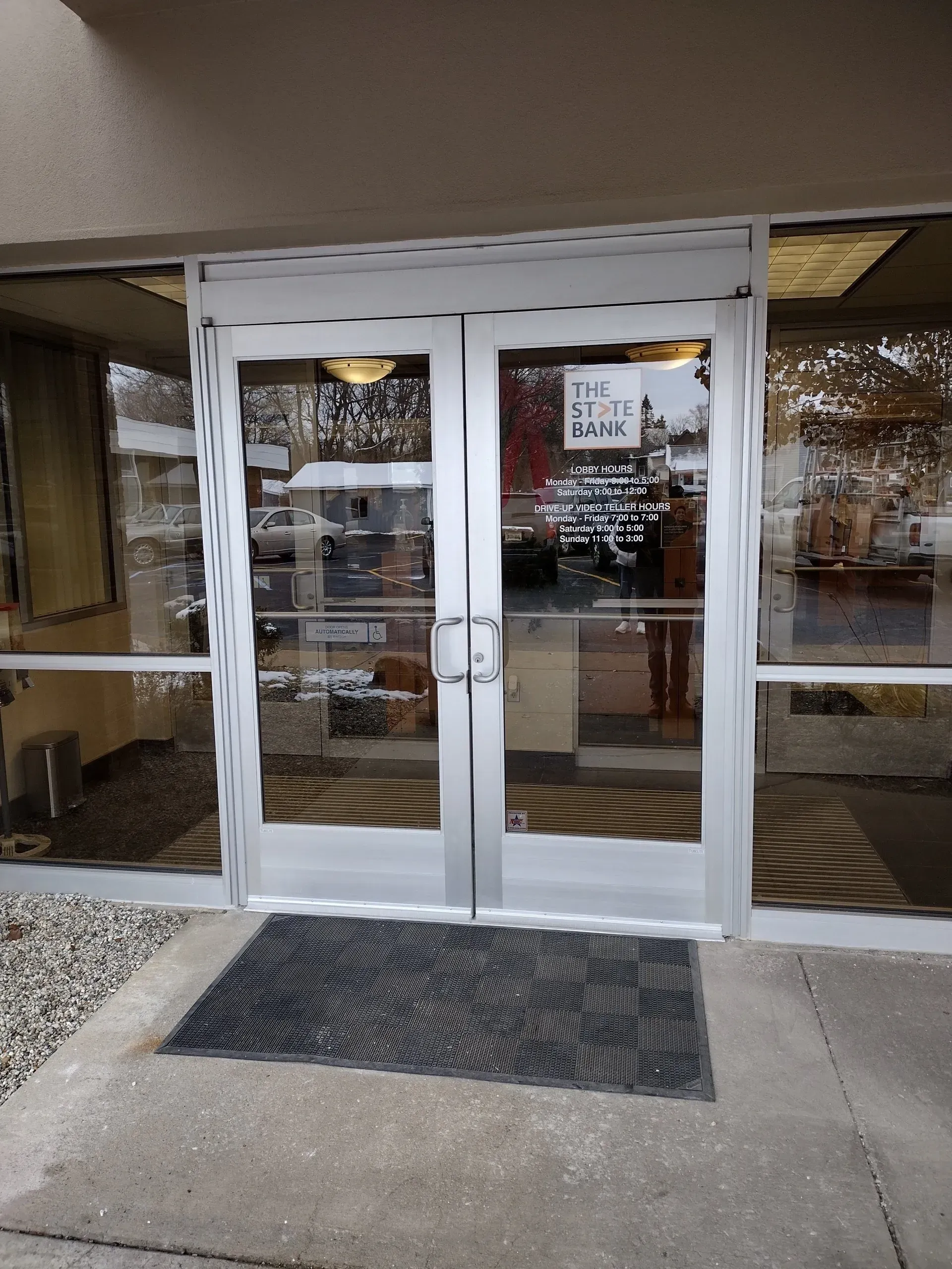 The front door of a building with a mat on the ground and glass double doors and side lights.