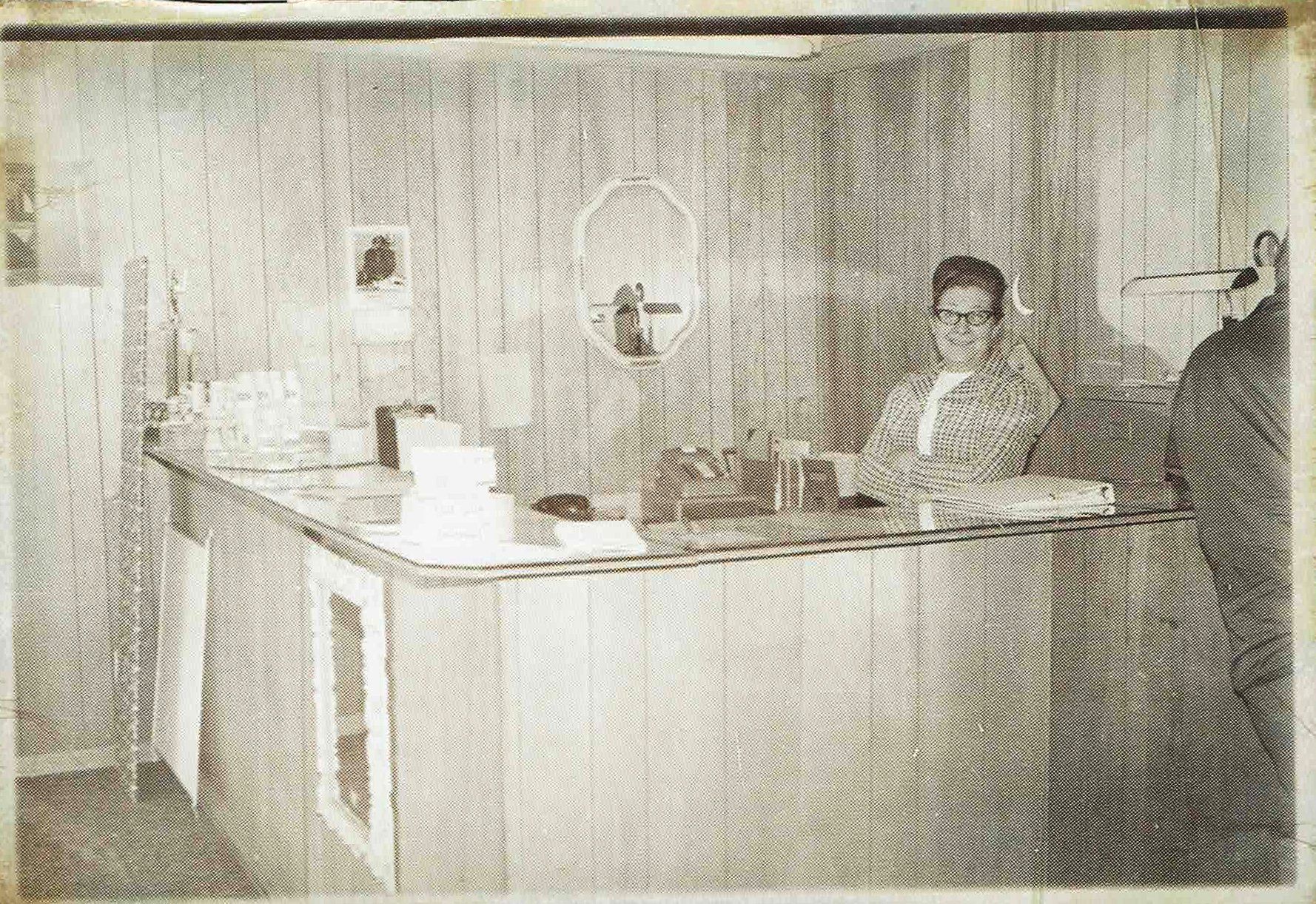 A black and white photo of a man sitting at a counter