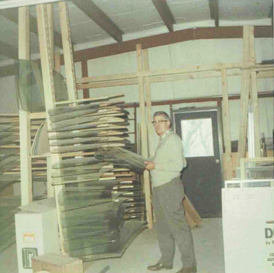 A man standing in a room with glass panes on racks.