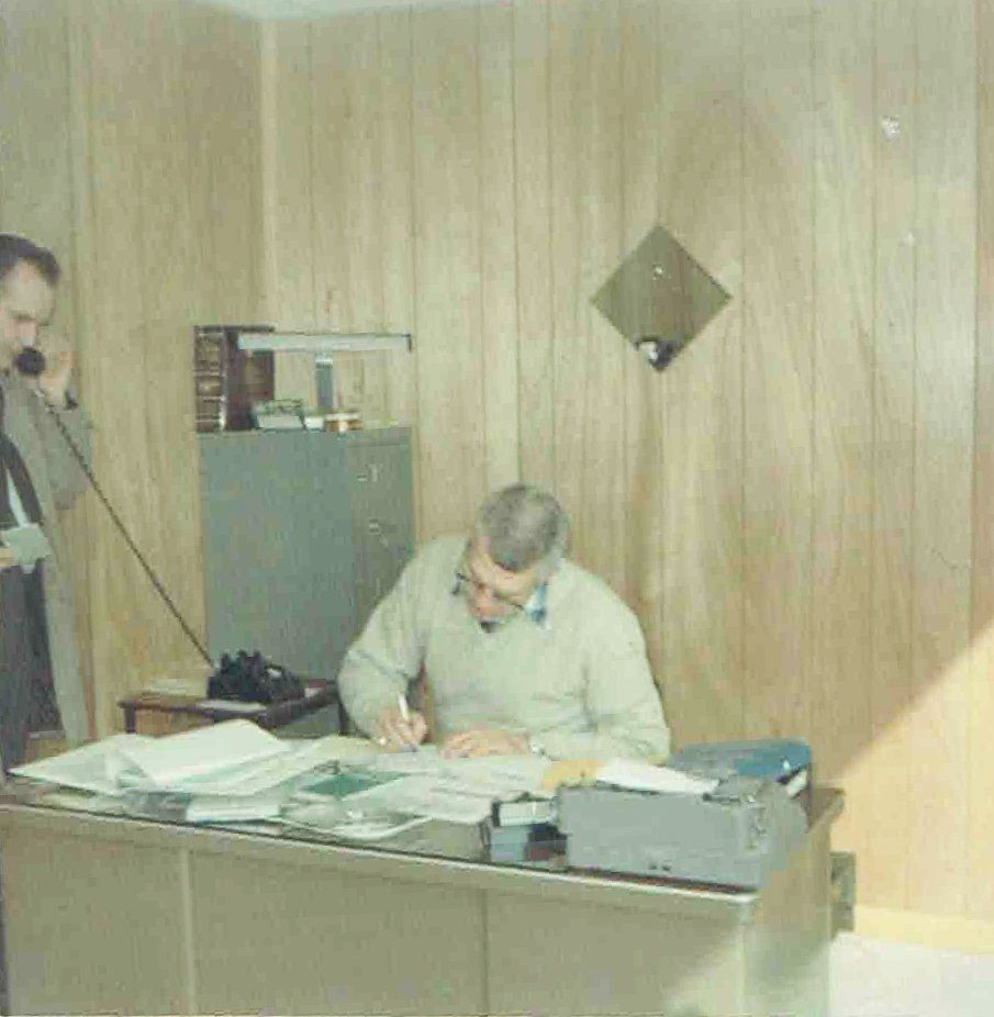 A man sitting at a desk talking on a phone