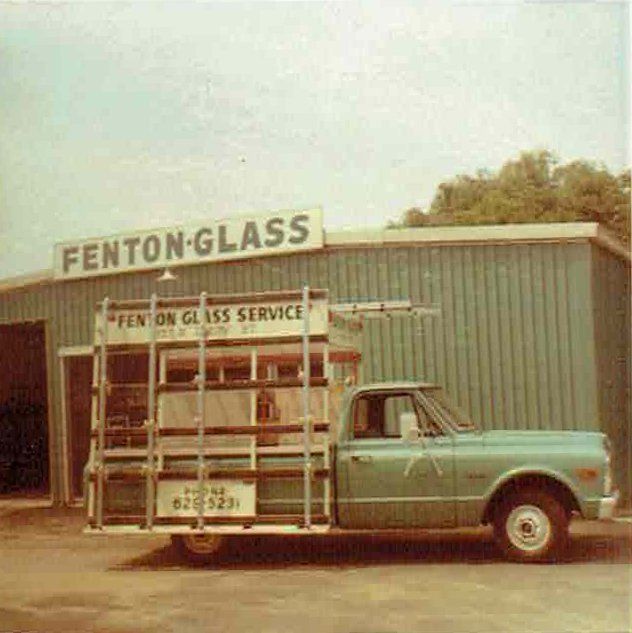 A truck is parked in front of a building that says fenton glass