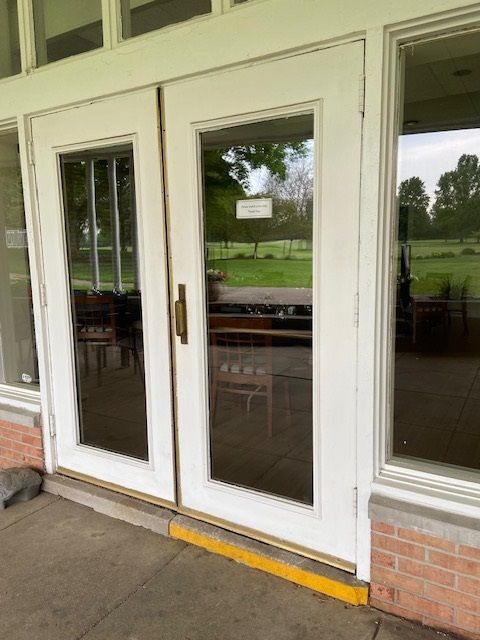 White double doors with glass panels, likely a building entrance. Yellow painted curb.