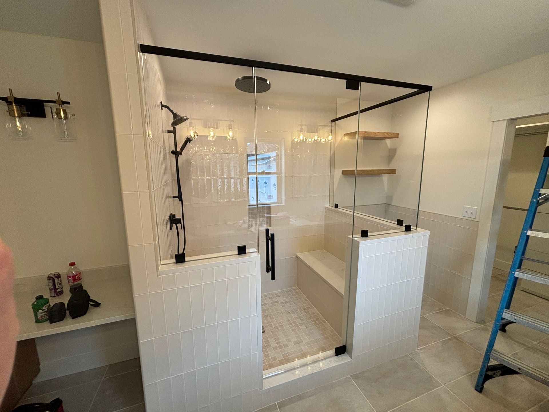 A bathroom with a walk in shower and a bench with a glass enclosure.