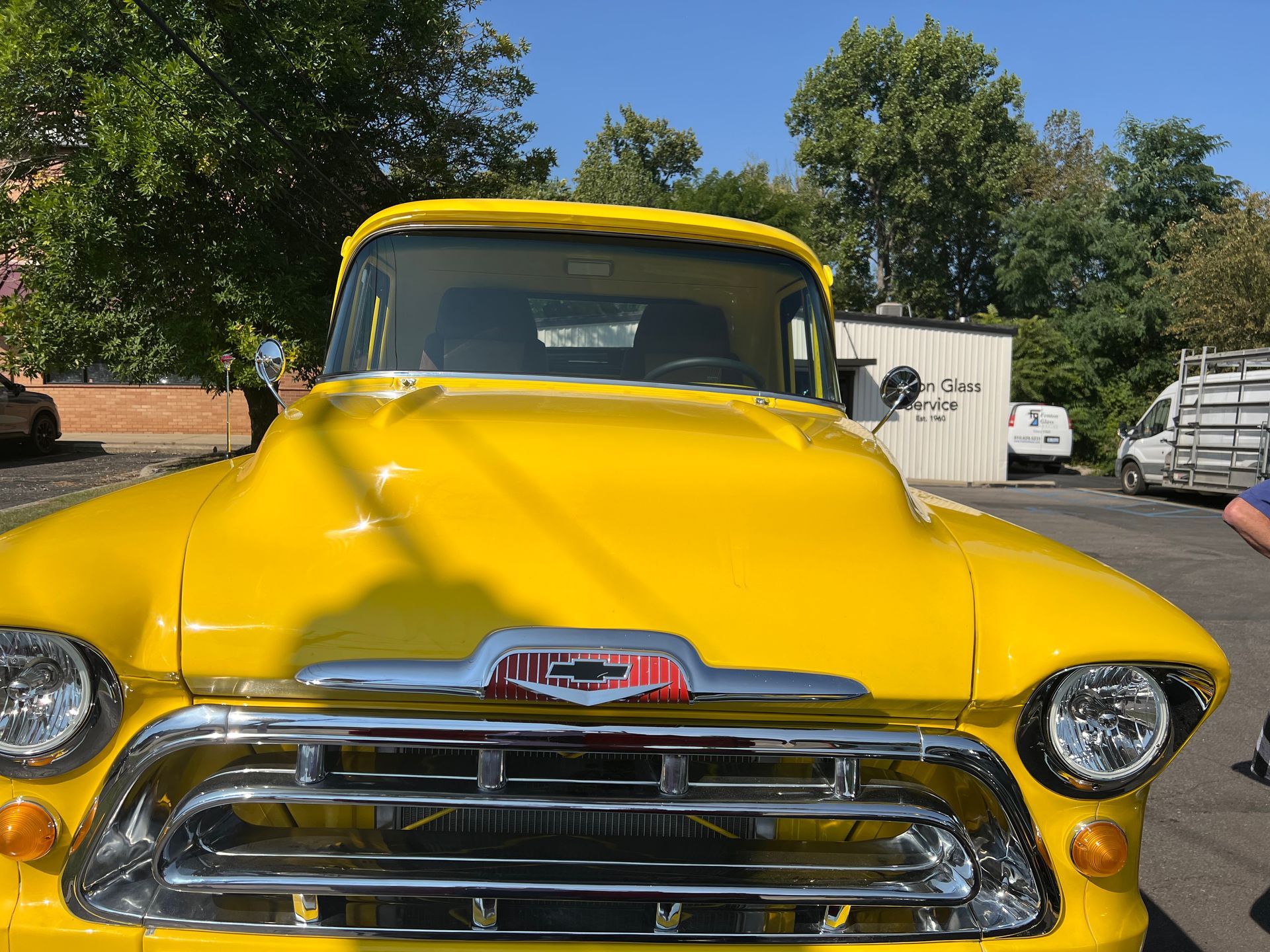 Bright yellow vintage Chevrolet pickup truck, chrome grill, sunny outdoor setting.