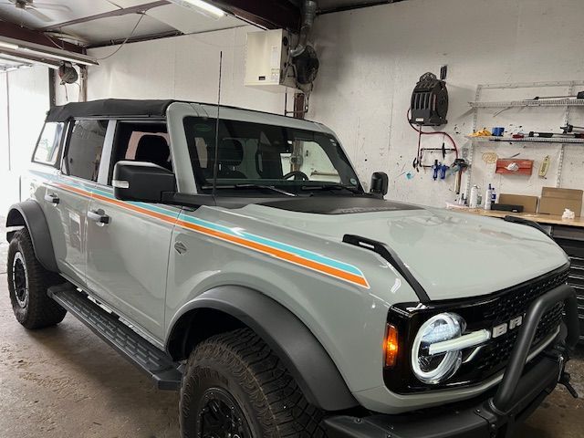 Gray Ford Bronco with orange and blue side stripes, black accents, and custom front lighting.