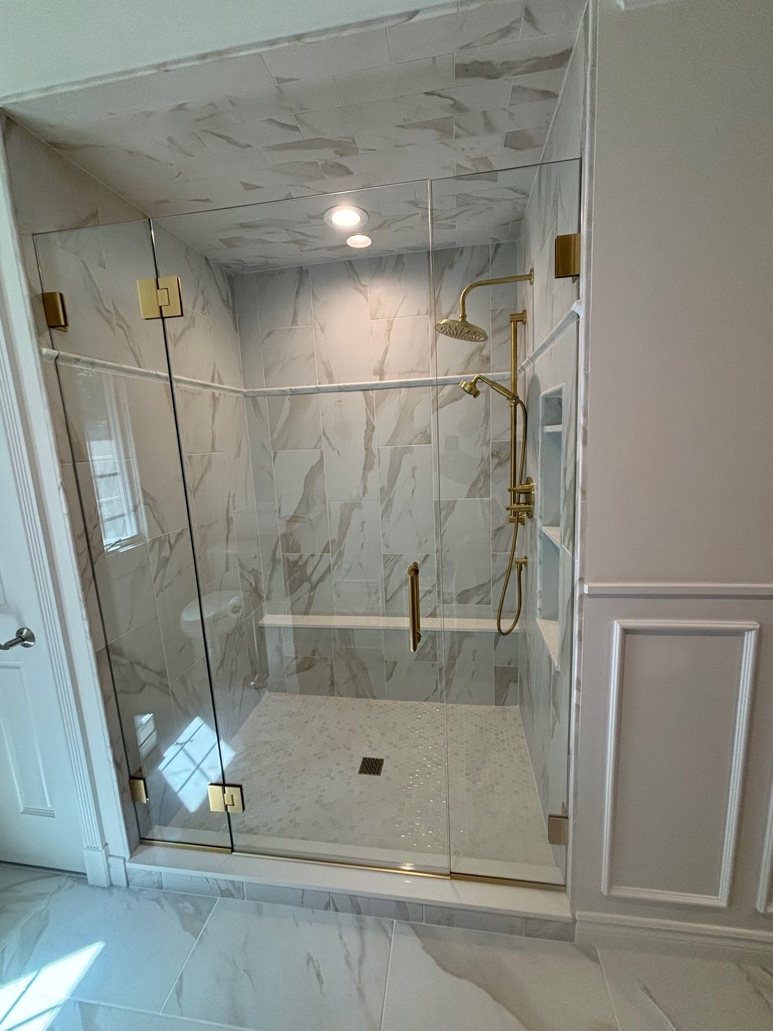 A bathroom with a walk in shower with a glass door.