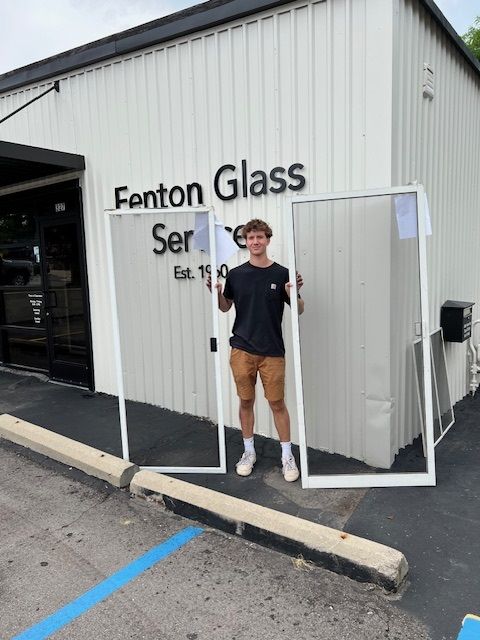 Man holding glass doorframes outside Fenton Glass Services building.