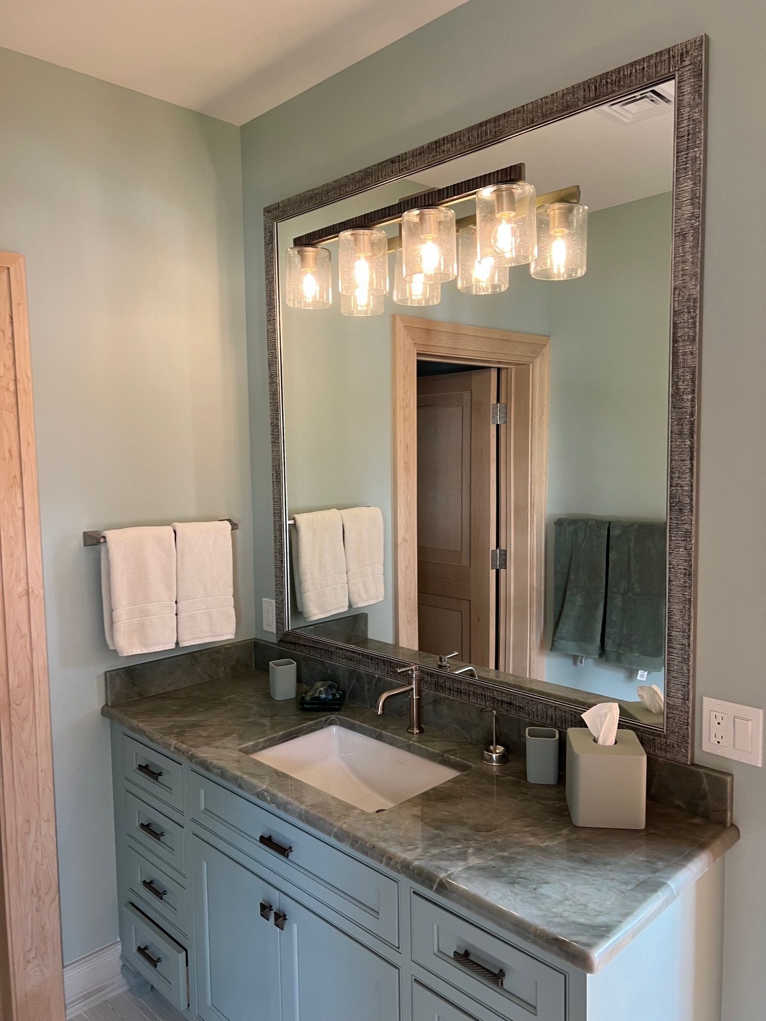 A bathroom with a sink , mirror and light fixture.