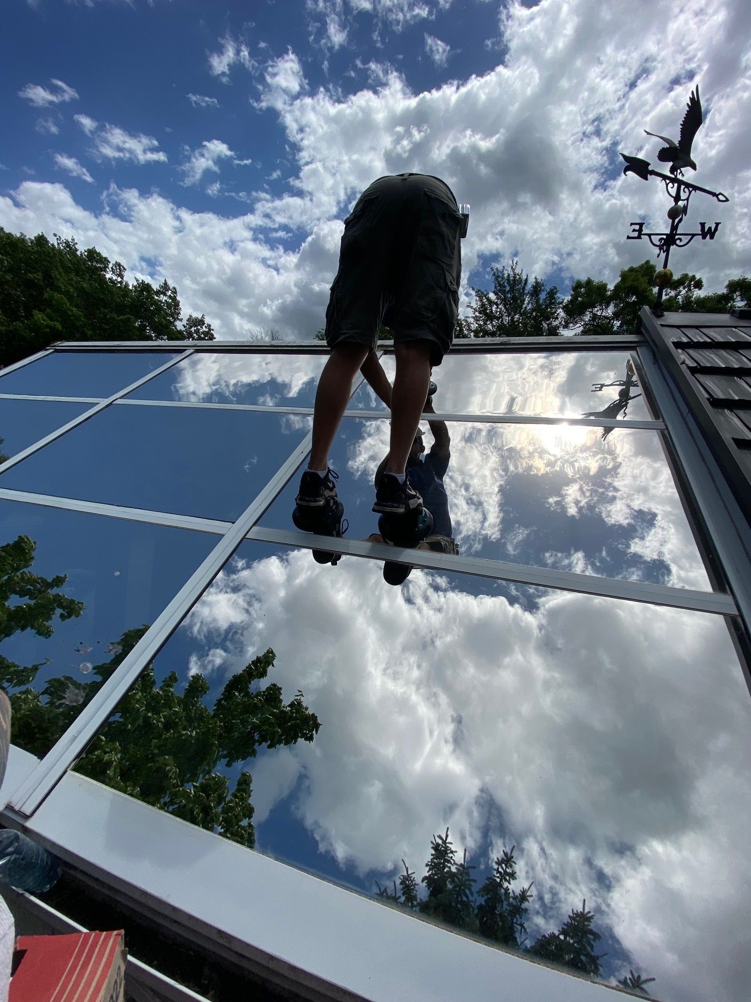 A man is standing on top of a glass roof.