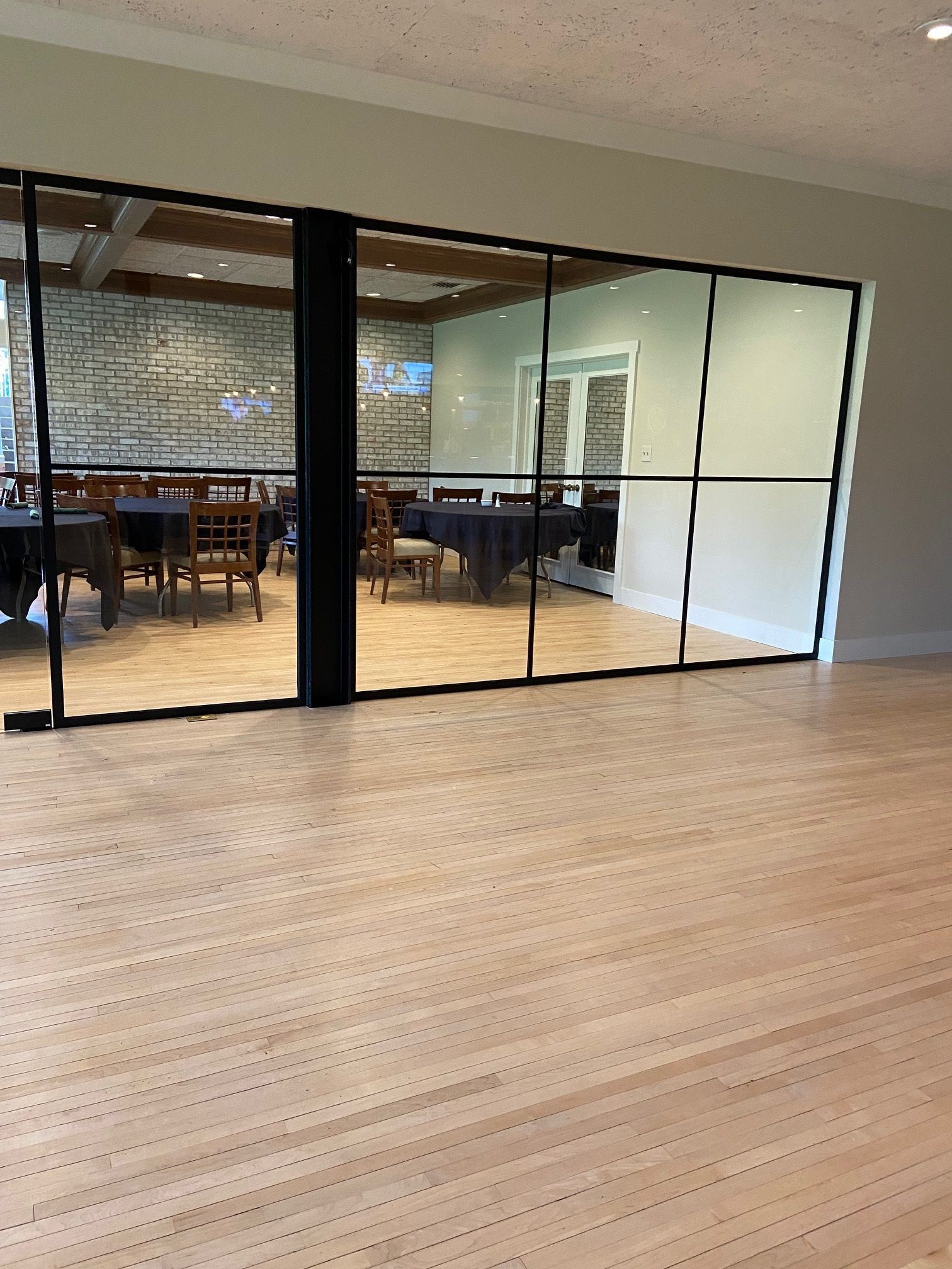 A room with tables and chairs behind a glass wall.