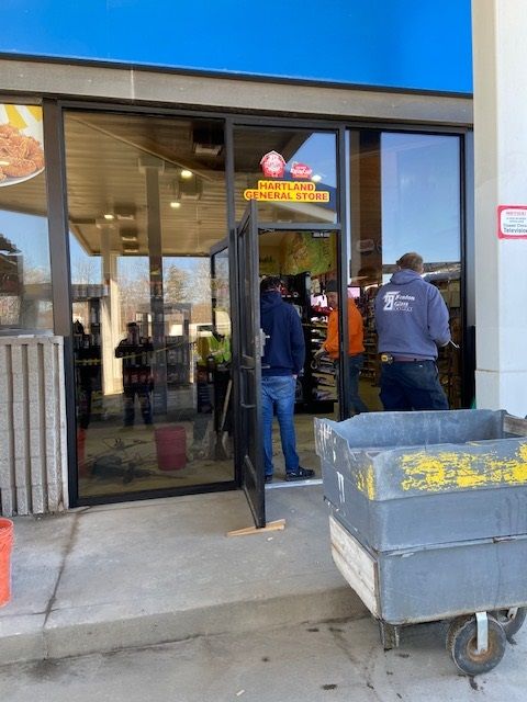 People at the entrance of a store, partially obscured. A cart is in the foreground.