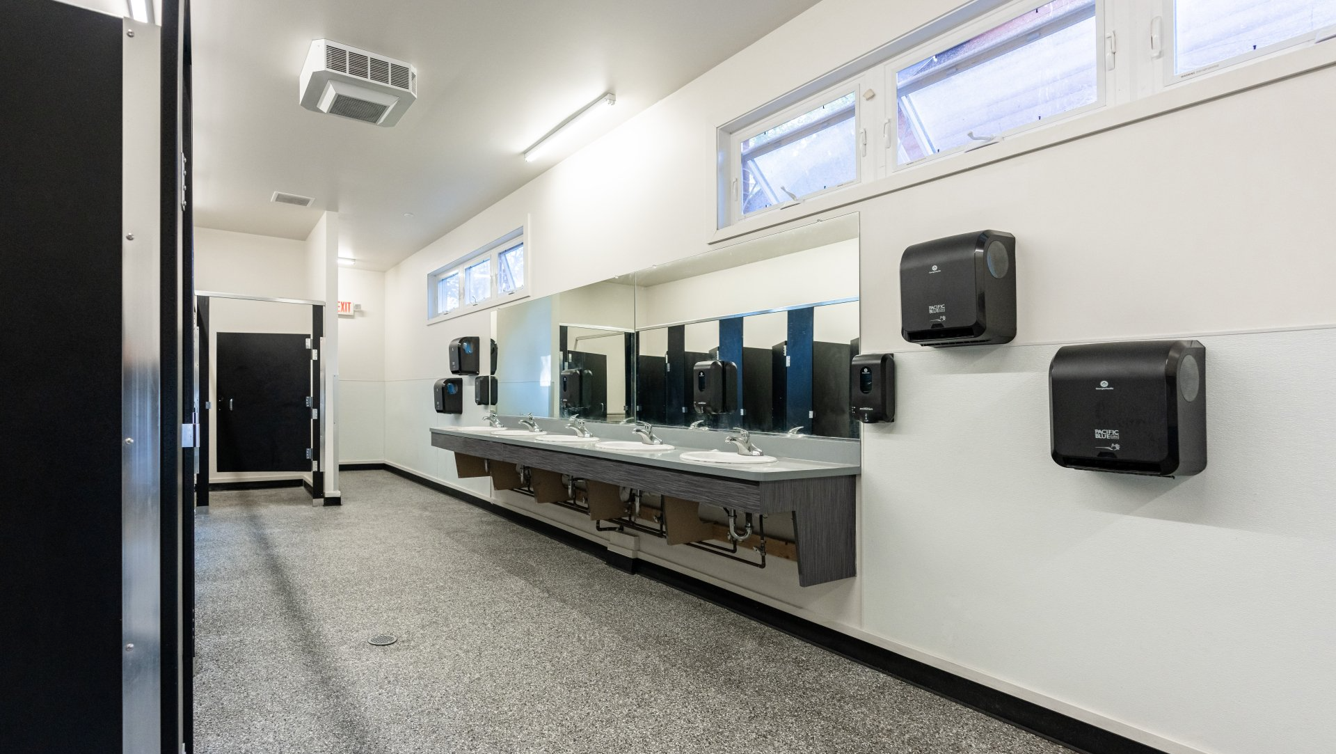 A public restroom with a long row of sinks and hand dryers.