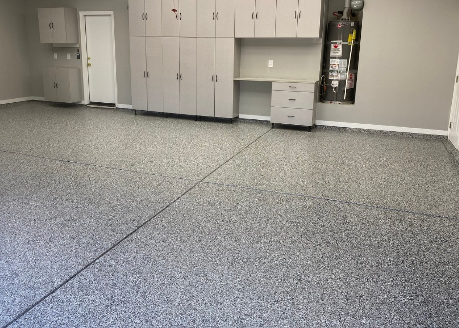 A large empty garage with a gray floor and cabinets.