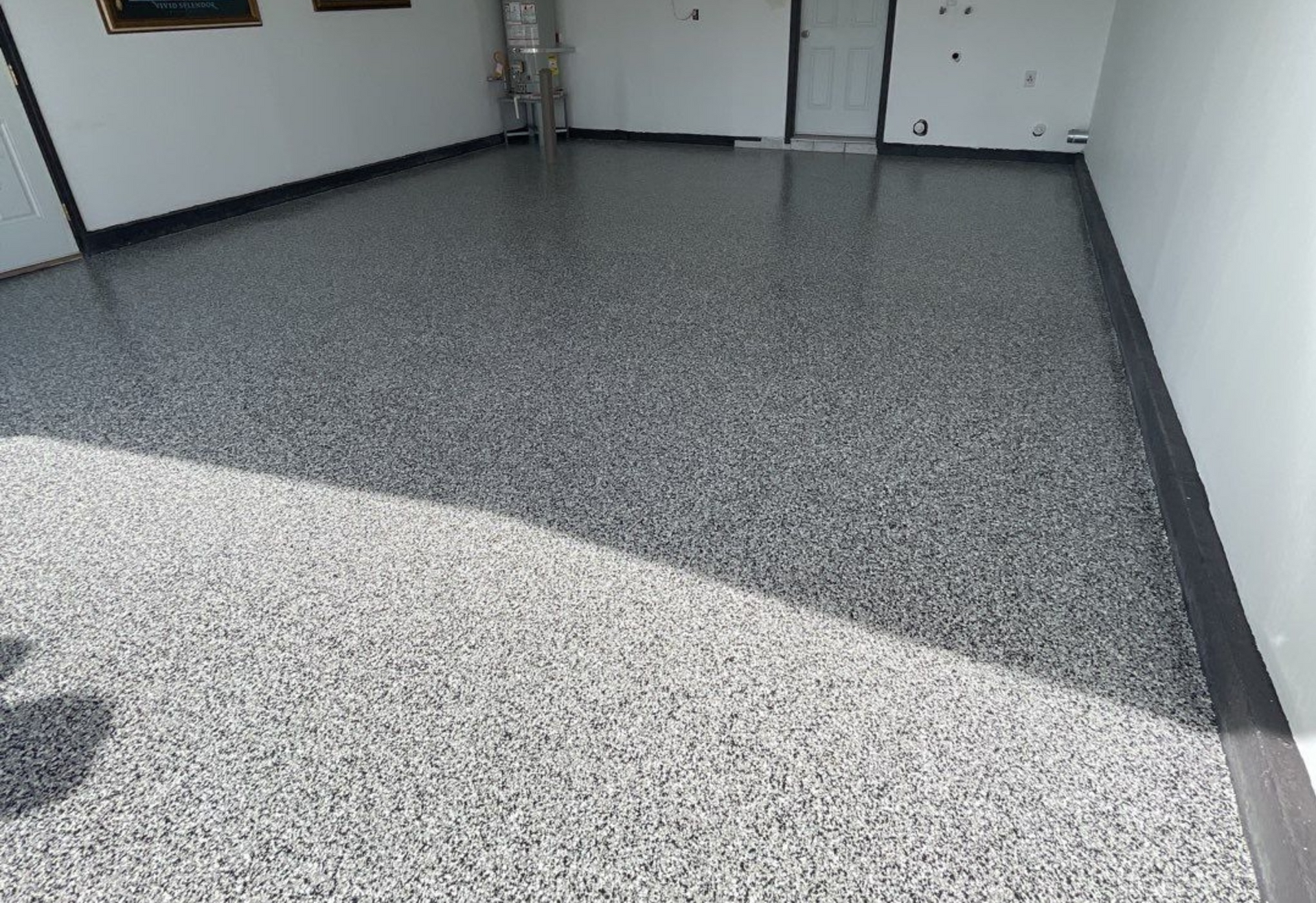 A garage with a gray and black floor and a white wall.