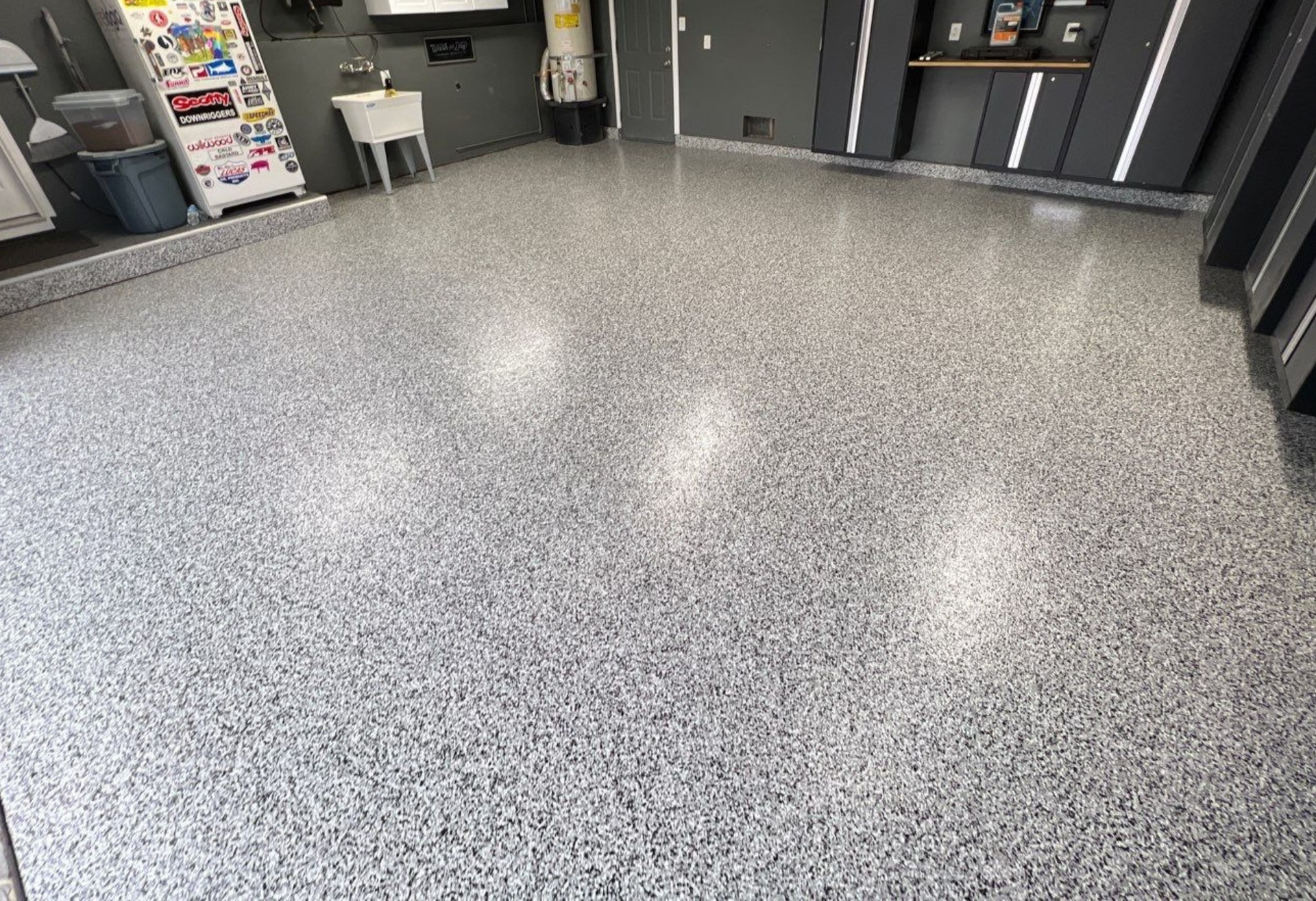 A garage with a gray floor and a sink.