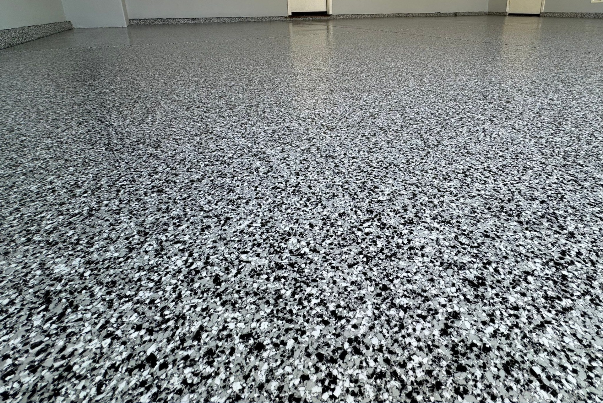 A close up of a gray and black concrete floor in a garage.