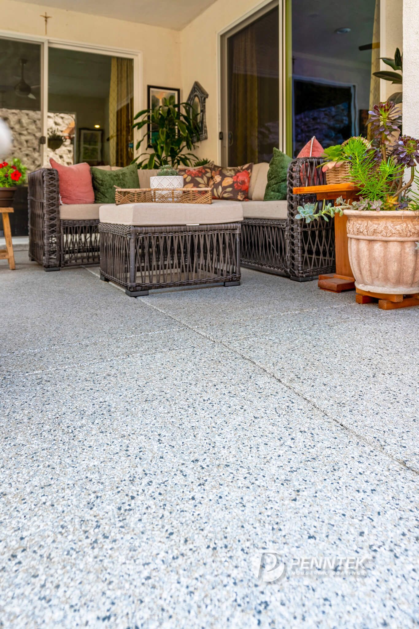 A patio with a couch , table , chairs and potted plants.