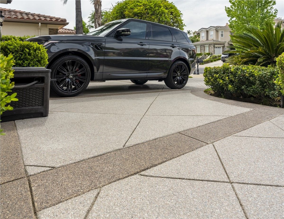 A black range rover is parked in a driveway next to a house.