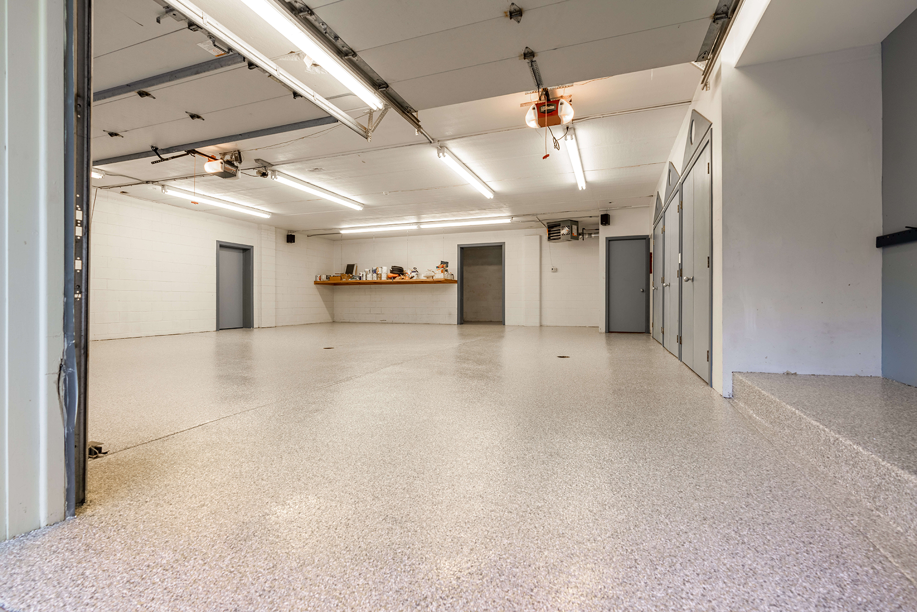 A large empty garage with a concrete floor and a garage door open.