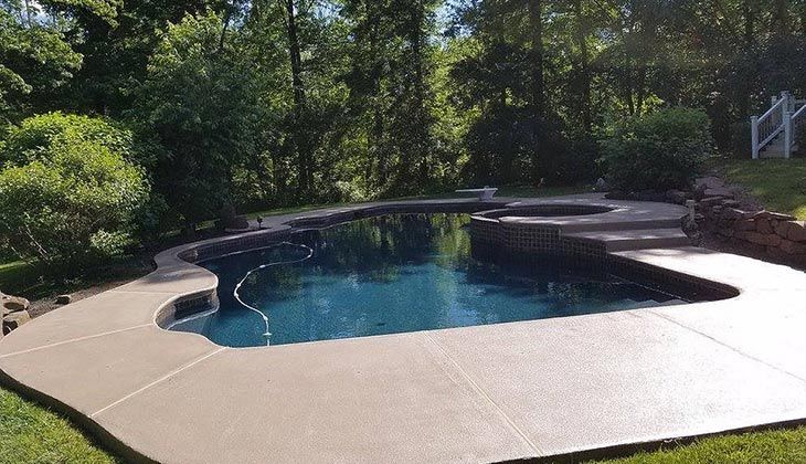 A large swimming pool surrounded by trees and a concrete deck.
