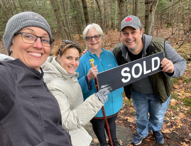 Four people smiling, holding a