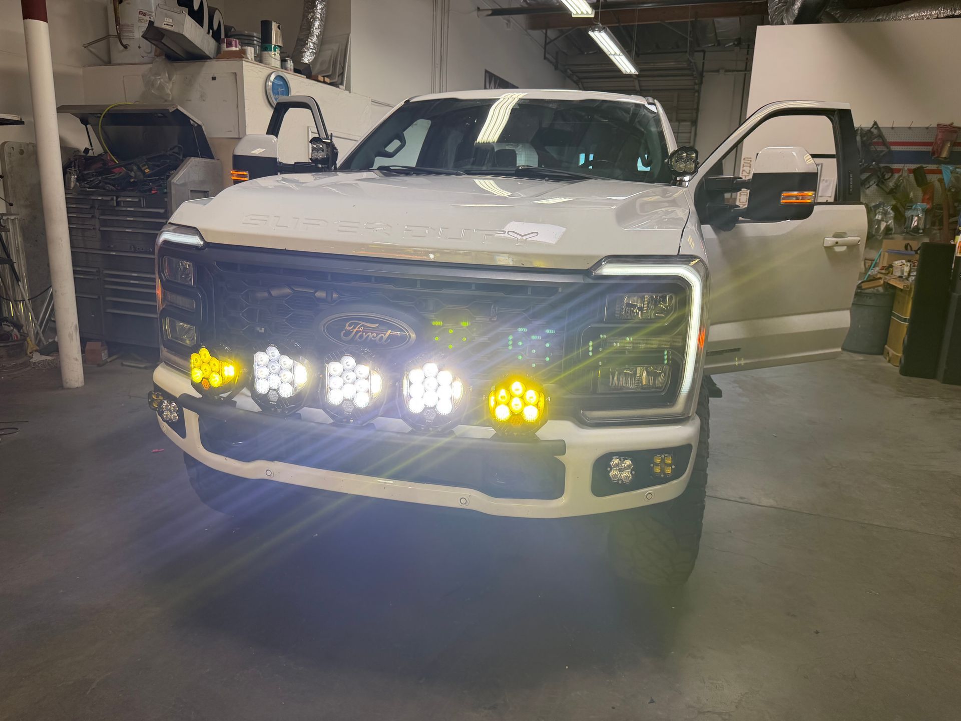 White pickup truck in a garage with bright front auxiliary lights turned on