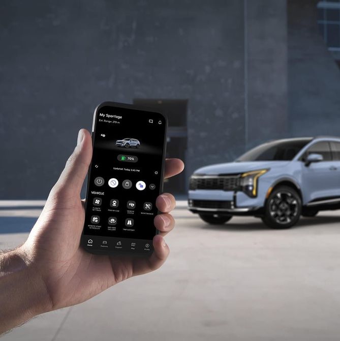 A hand holds a smartphone displaying a car app, with a blue SUV parked in the background.