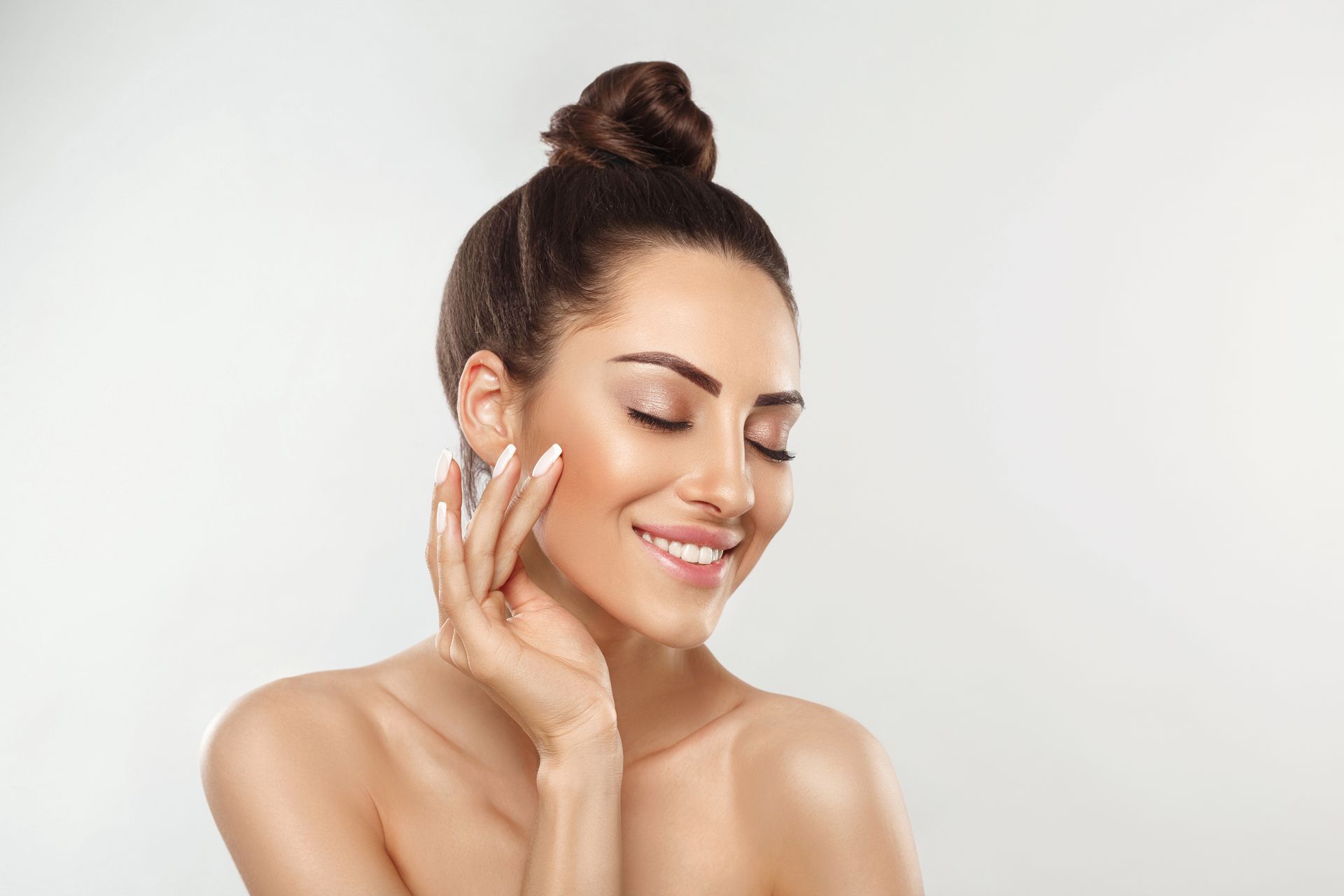 Woman with glowing skin smiling softly, showcasing results of professional dermatology services.