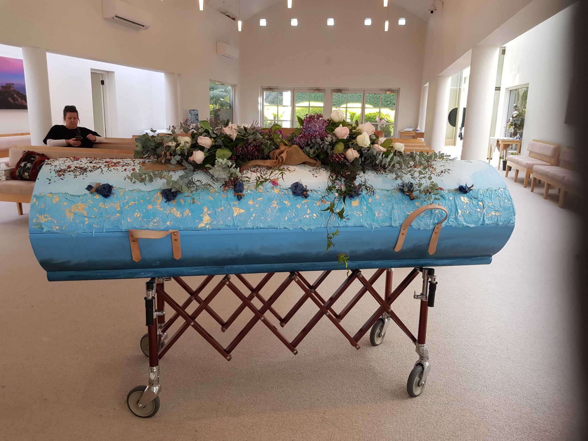 A blue coffin with flowers on top of it in a church